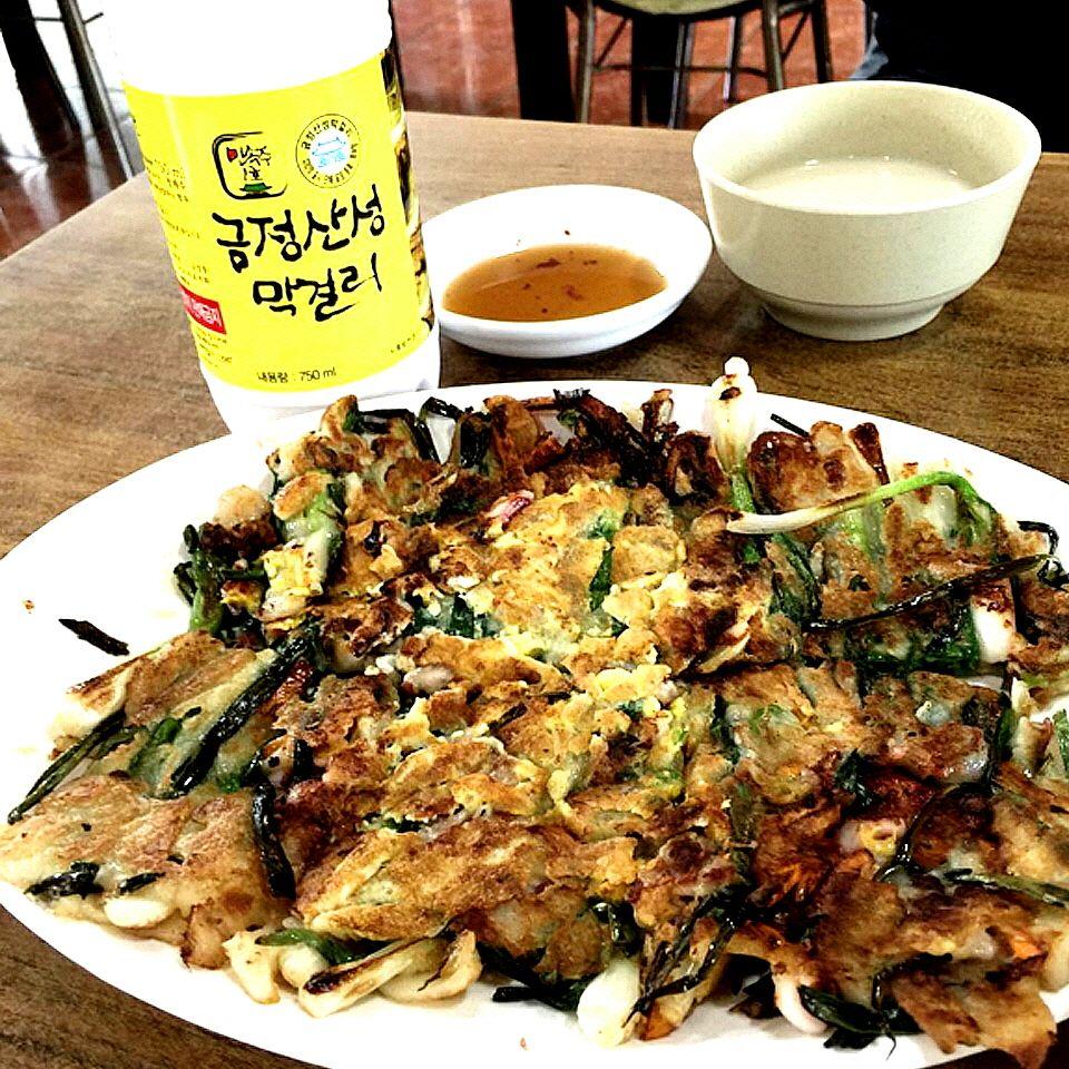 dish of famous Dongrae pajeon, Korean savory pancake made with meat and vegetables, served with tableware and drink.