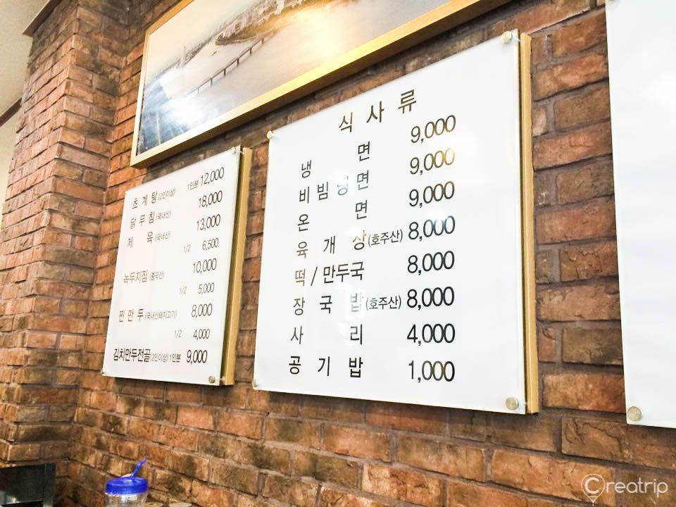 exterior of 평래옥, a historic building in Korea, with brick facade and wooden signage featuring a menu.