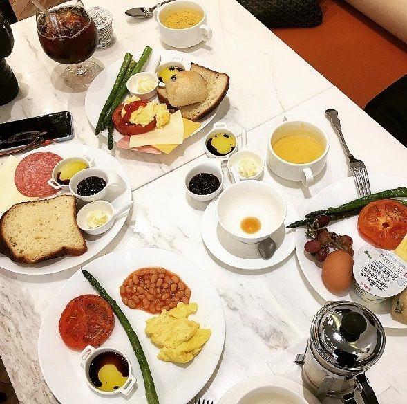 A delicious spread of Korean cuisine including a plate of The Famous Lamb, bread, coffee, and fruit on a table decorated with tableware and dishware.