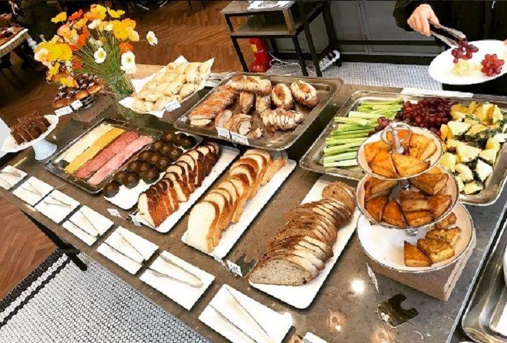 A table filled with food, including bread, coffee, and various dishes, including a plate of 더페이머스램.