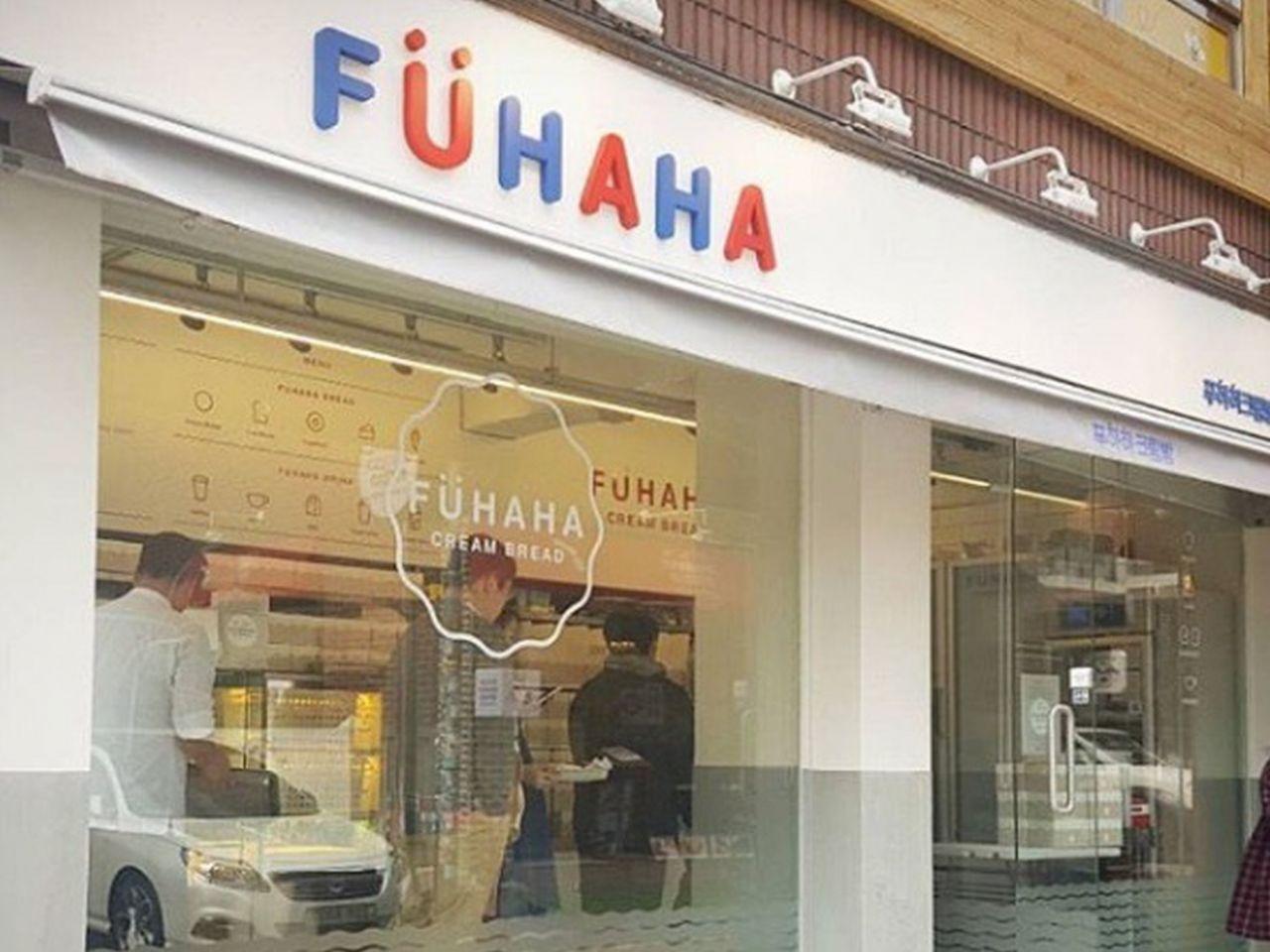 Exterior of a Korean bakery selling tires, with a car and a cream bread product on display.