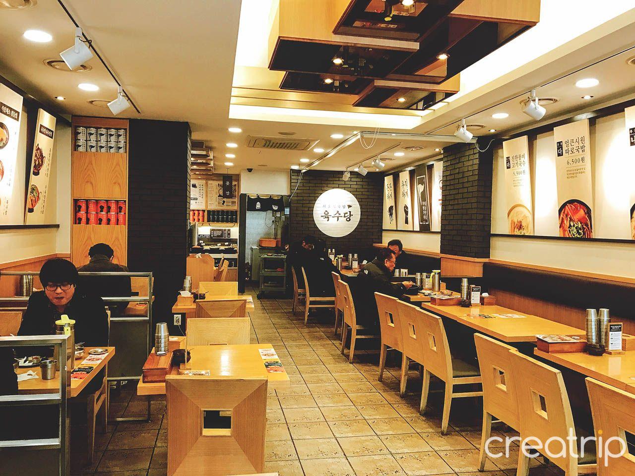 Interior of 육수당 충무로점 restaurant with tables, chairs, and unique decor.