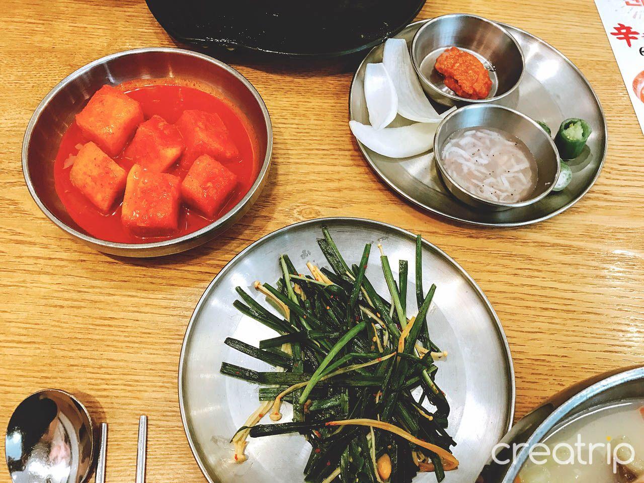 A spread of Korean dishes including 밑반찬, served on tableware from 육수당 충무로점.