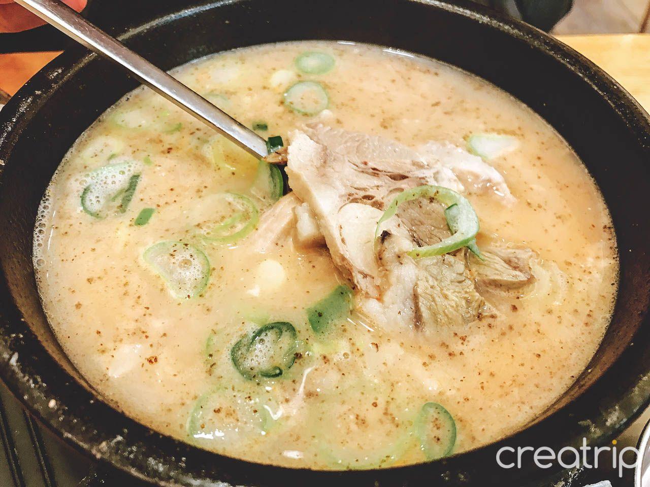 Delicious 육수당 충무로점 수육 국밥 - a traditional Korean cuisine featuring meat, veggies & rich soup broth.