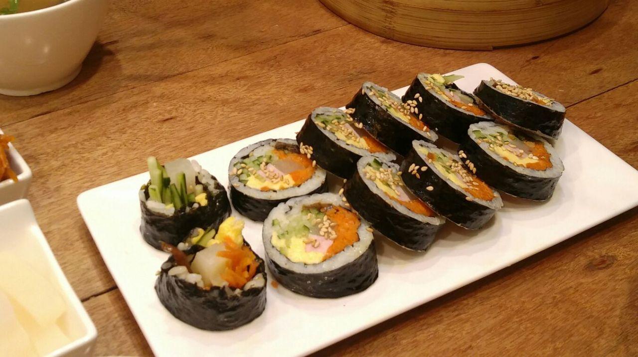 A table filled with Korean cuisine dishes including sushi, kimchi, and kimbap at Baruda Kim Seonseang restaurant in Seoul.