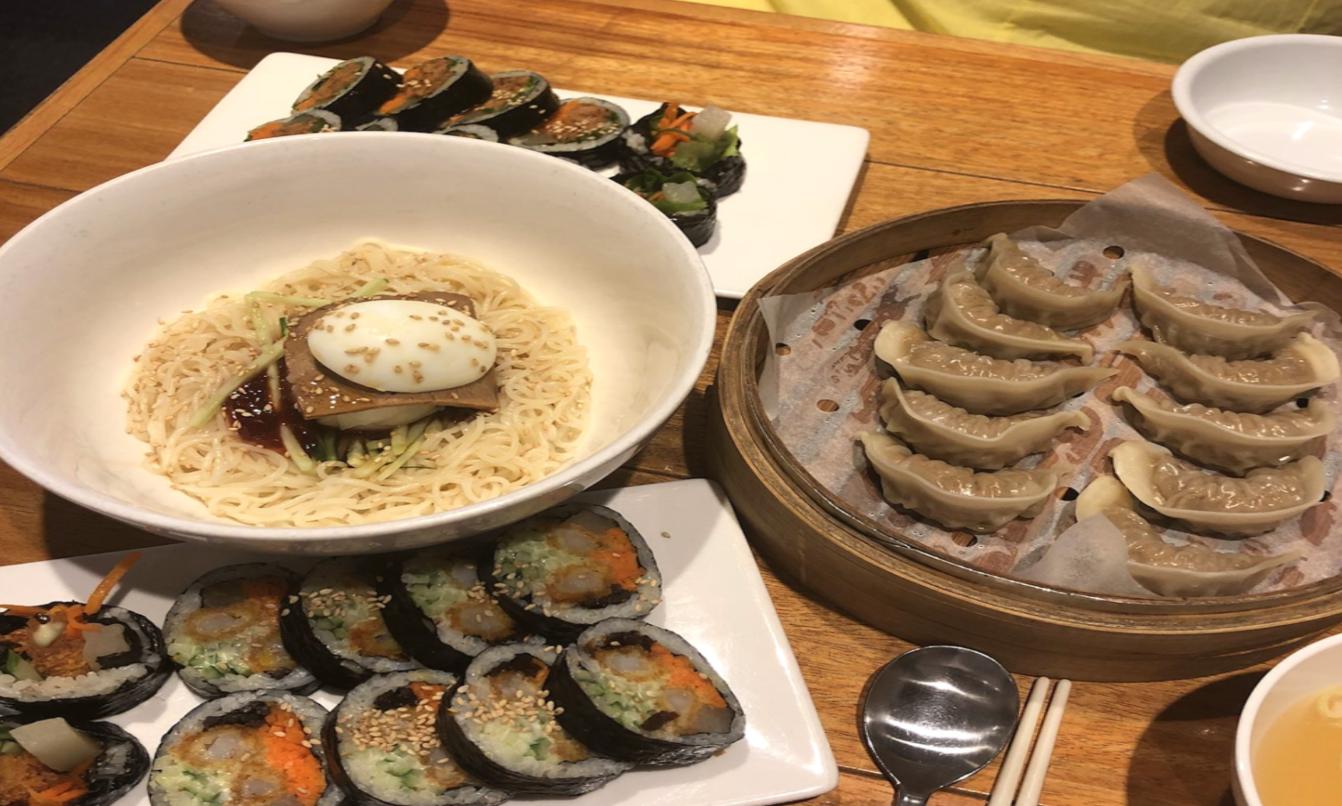 Colorful Korean dishes including bibim noodles, mandu dumplings, and kimbap served at Baruda Kim Seonseang restaurant in Hongdae.