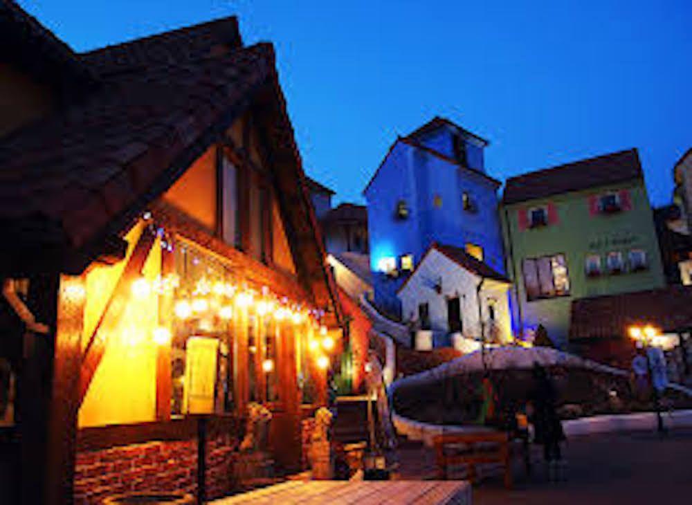cityscape of a mixed-use town with French and Italian influences at dusk featuring flowerpots, buildings, and roads.