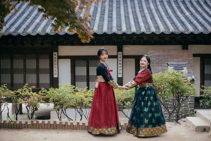 Visit Gyeongbokgung hanbok rental shop for a leisurely travel dressed in formal wear amidst the temple's lush greens and traditional houses.