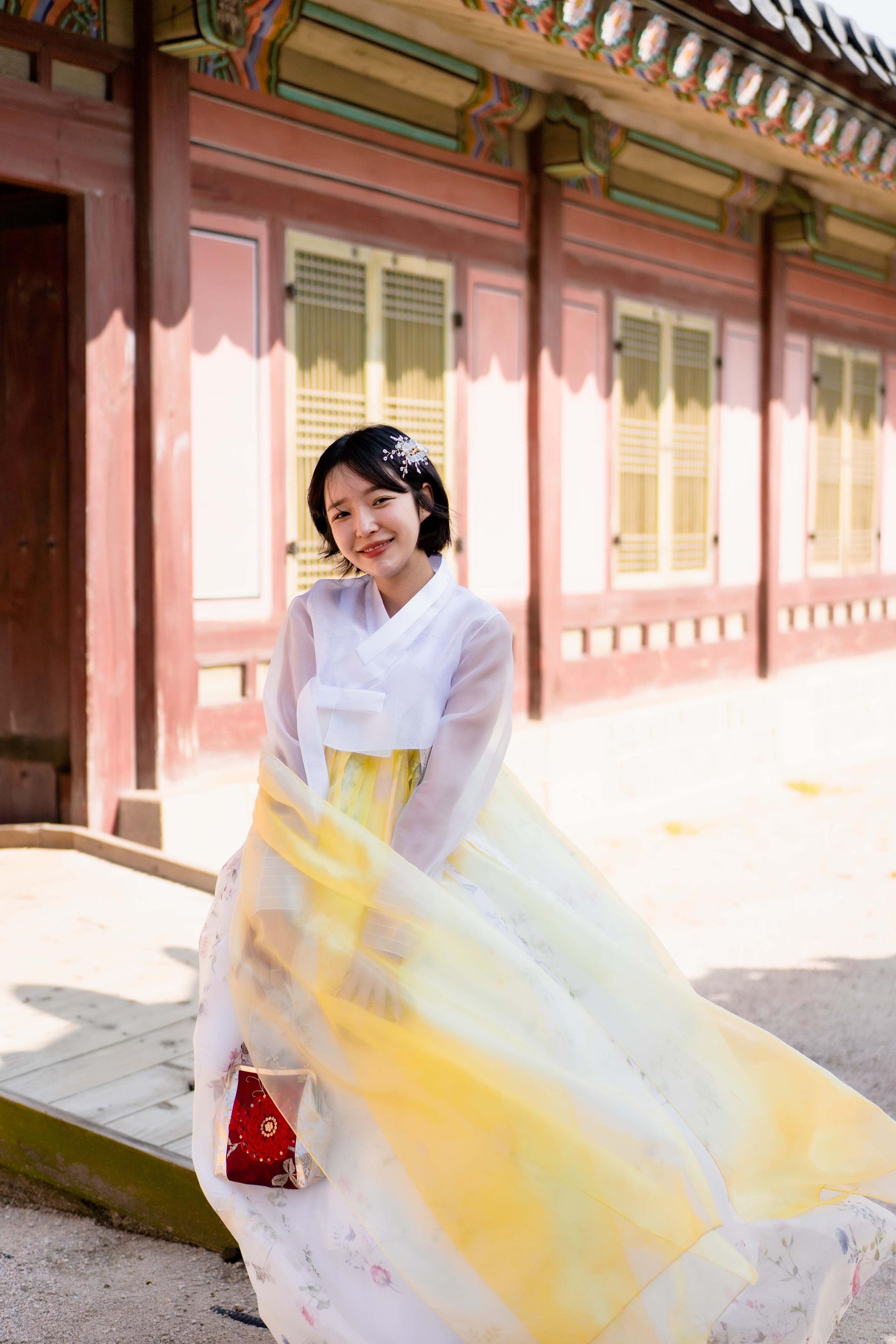 A happy couple flashes a smile outside a hanbok rental shop in front of Gyeongbokgung temple.