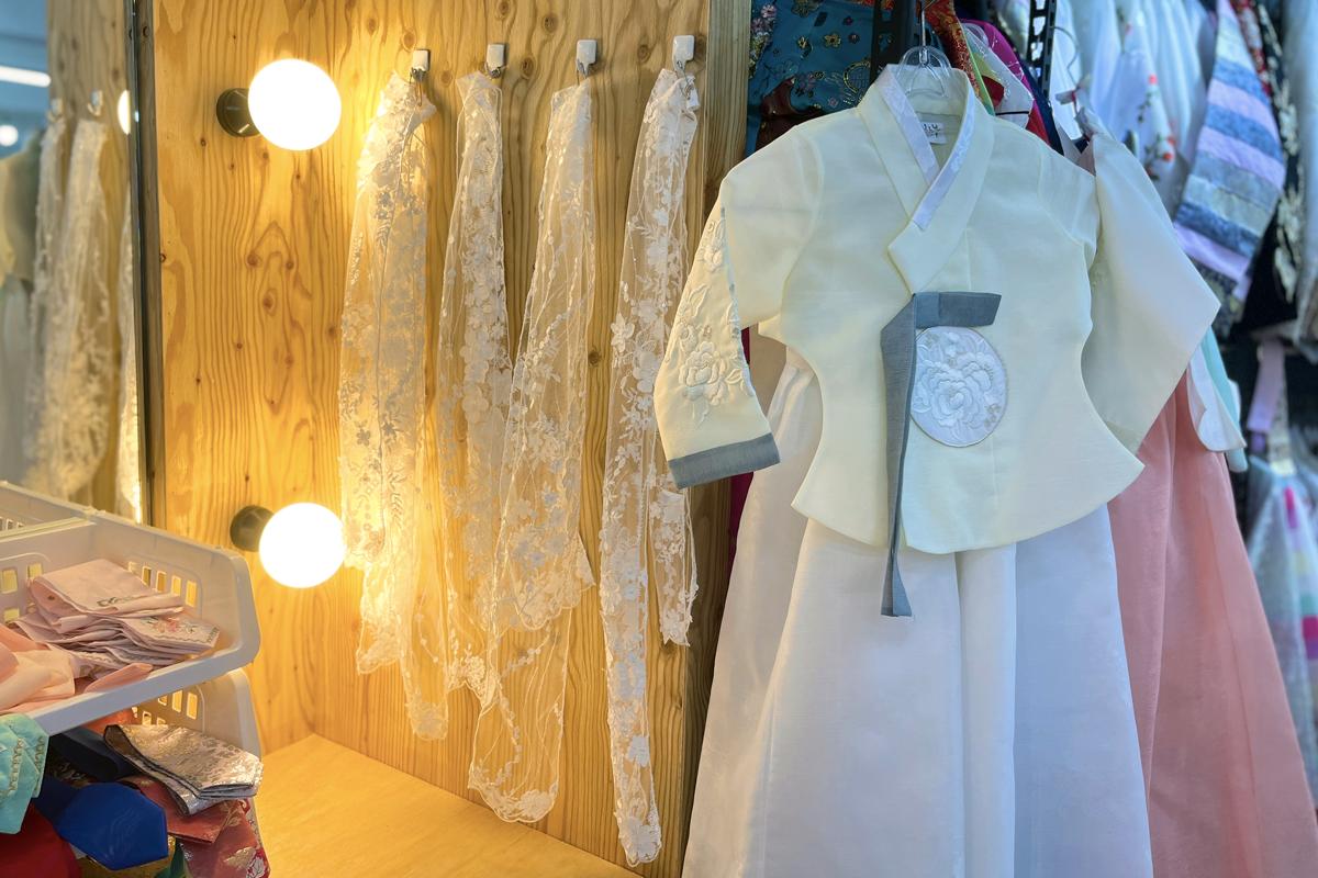 Interior of Gyeongbokgung hanbok rental shop with wood building and hangers showcasing one-piece garments for formal wear and day dresses.