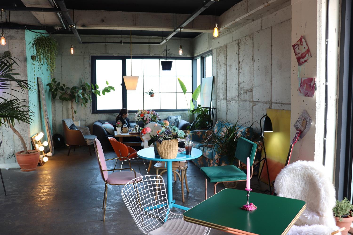 rooftop cafe with plant-filled furniture, tables, chairs, and flowerpots overlooking a building and houseplants in window. Ideal for real estate and property.