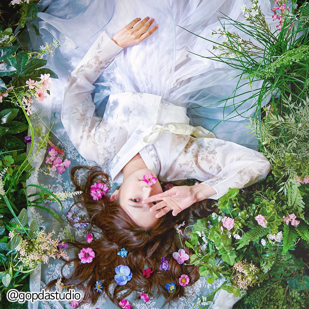 A model poses in a pink Hanbok dress with flower bouquet at Busan Hanbok rental shop.