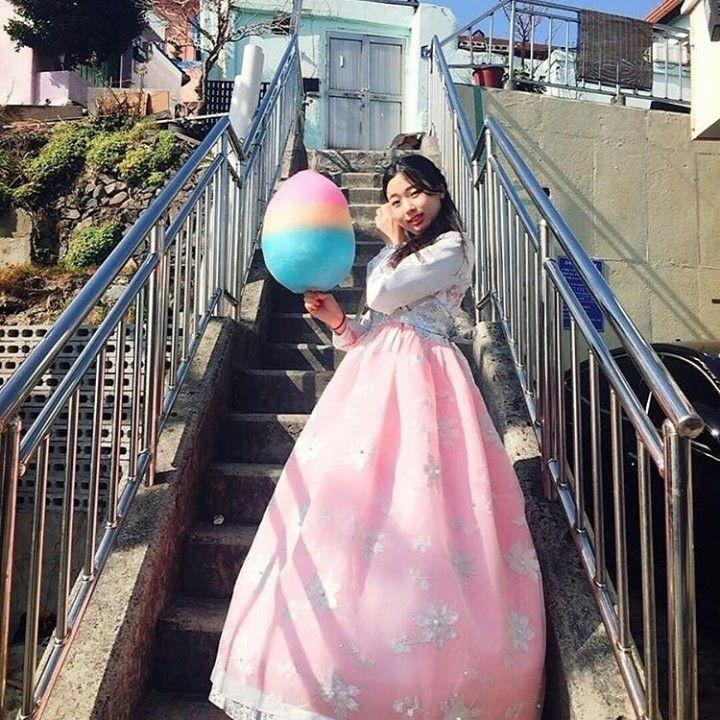 Smiling model poses in pink hanbok dresses in front of Hanbok rental shop.