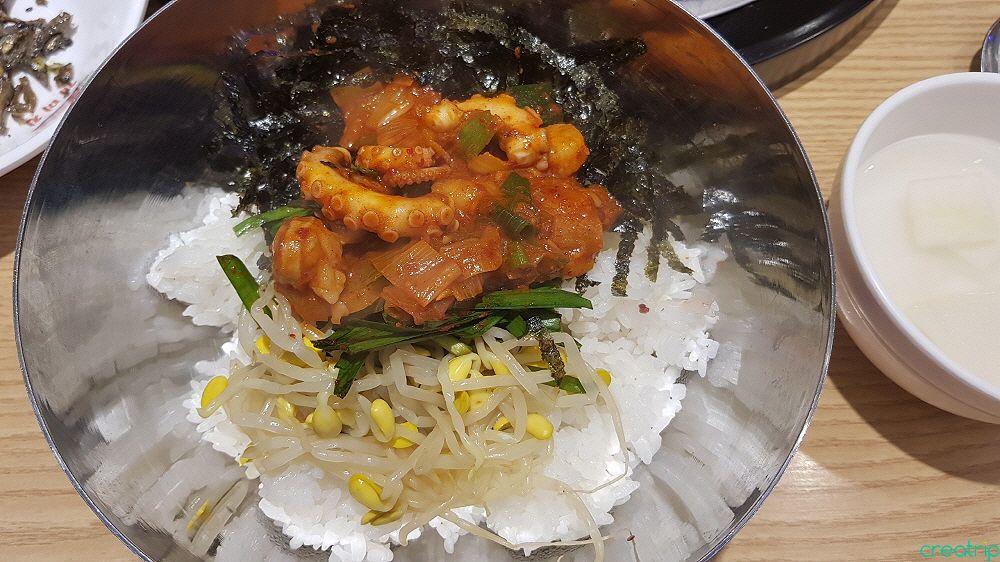plate of spicy stir-fried squid with white rice, accompanied by side dishes and tableware at a Korean restaurant in Hongdae.