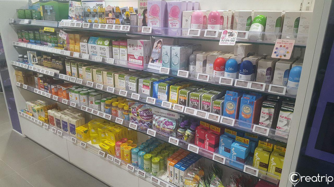 Shelving with convenience store products - plastic bottles, snacks, and publications - at Olive Young Hongdae branch in Korea.