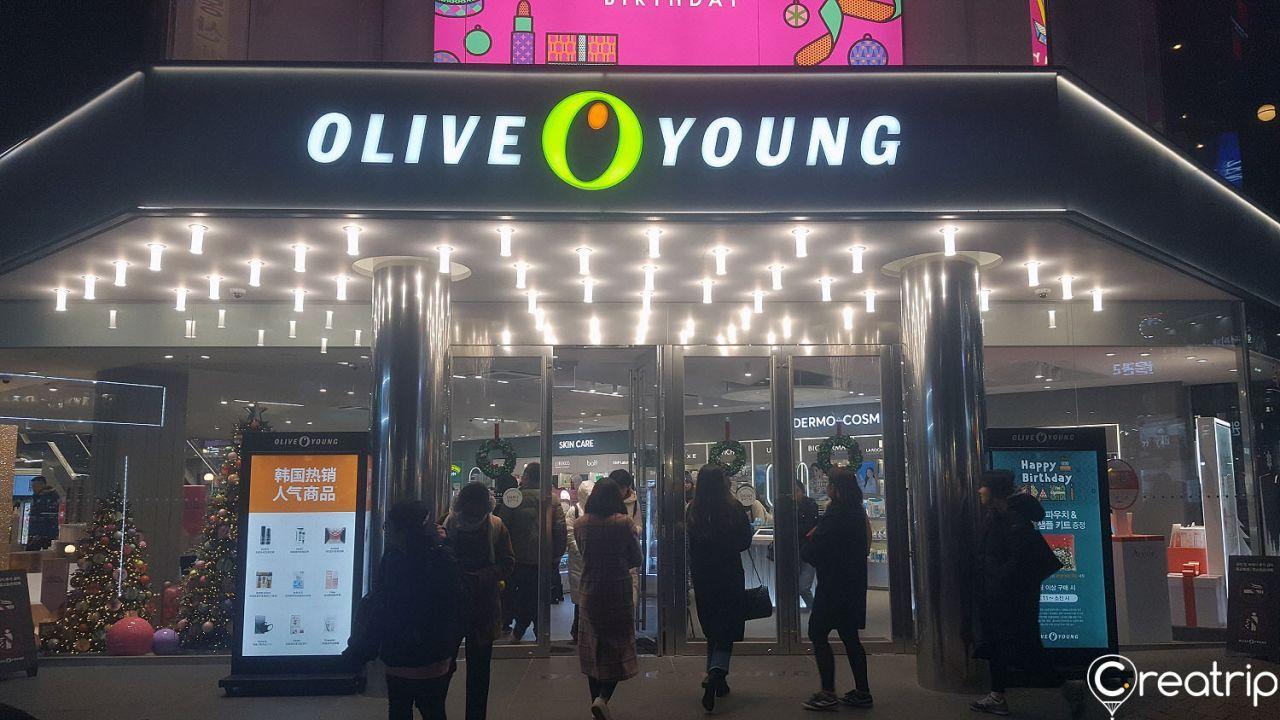 Exterior of Olive Young store at Hongdae station, Seoul with signage, electronic display device and retail fixtures.