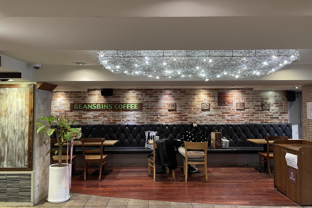 Interior of Beansbins dessert cafe in Myeongdong, Seoul featuring stylish furniture, lush plants, and modern flooring.