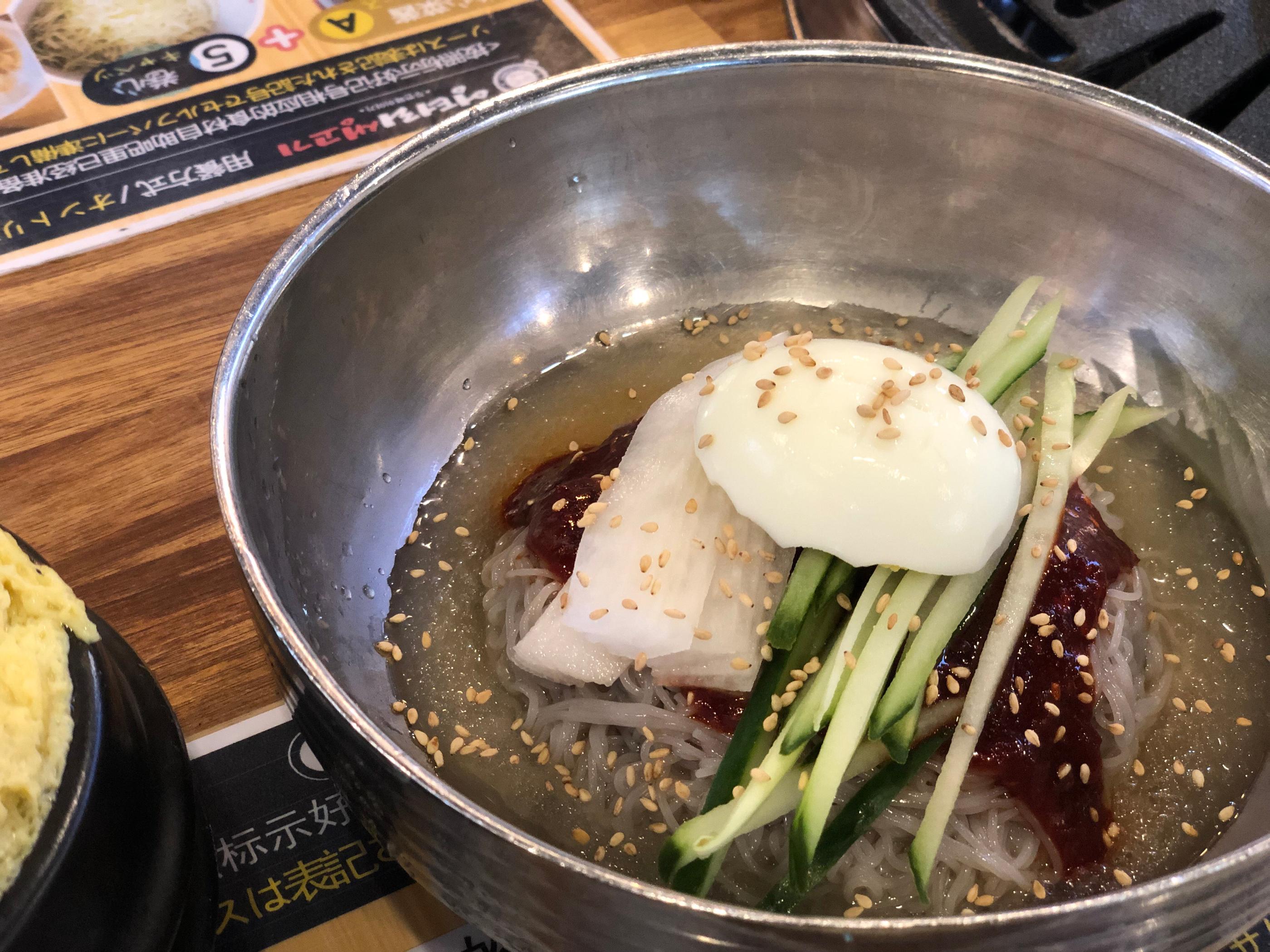 cold noodles, and tableware on a wooden table at 엉터리생고기 홍대점 in Korea.