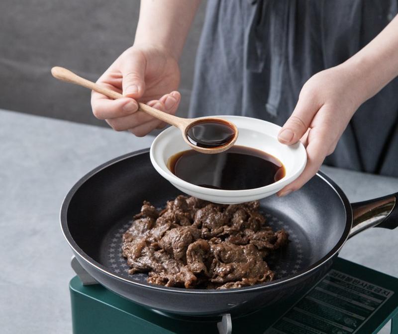pan full of meat getting seasoned by korean brand paikcook's Stir-fry Sauce by Baek Jongwon
