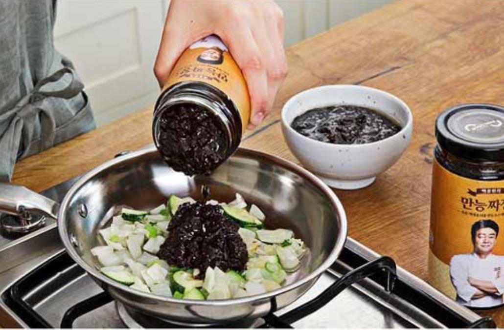 korean brand paik cook's jajang sauce by baek jongwon poured onto veggies on a pan