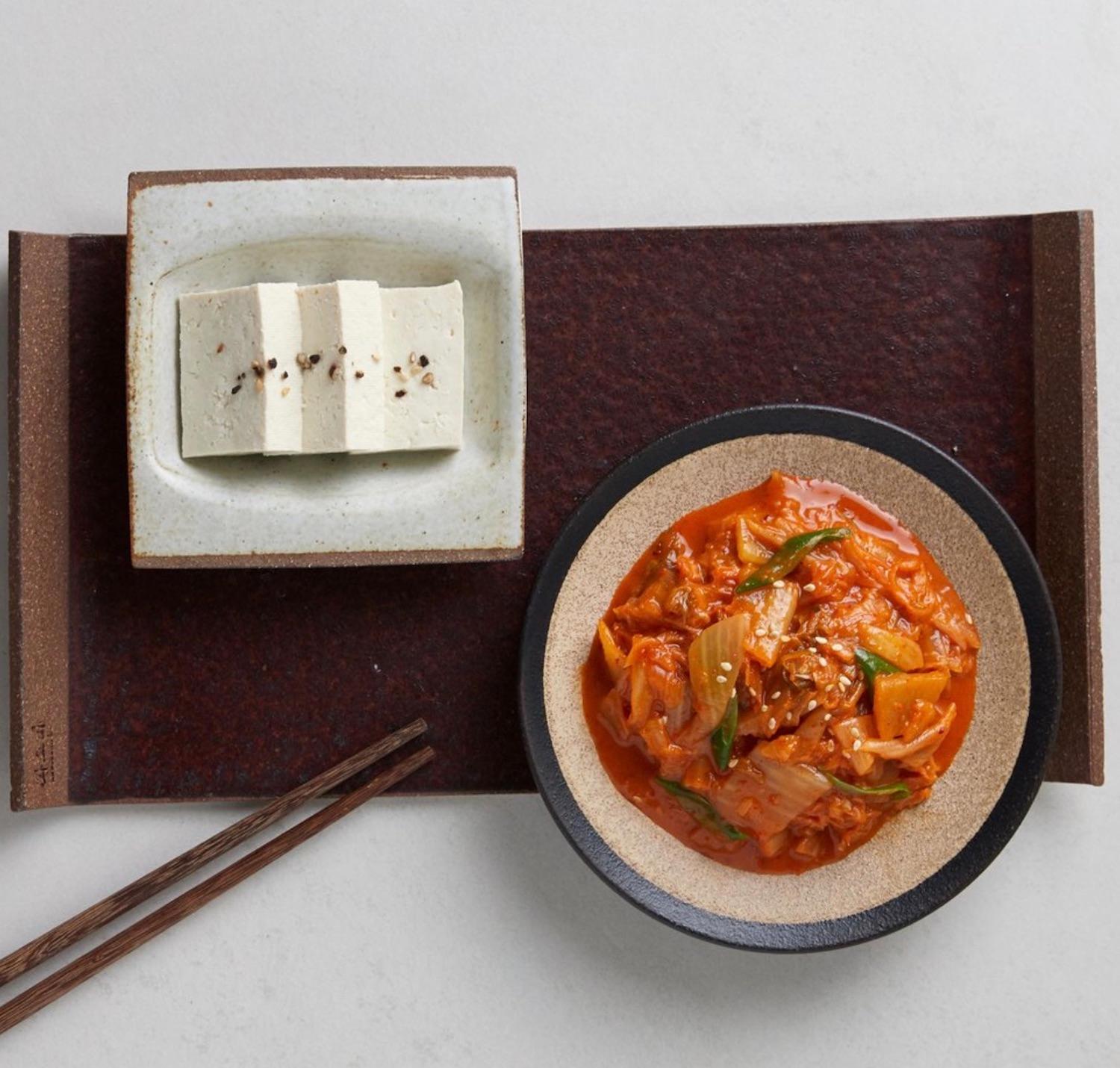 korean brand bibigo's stir-fried kimchi in a dish next to tofu