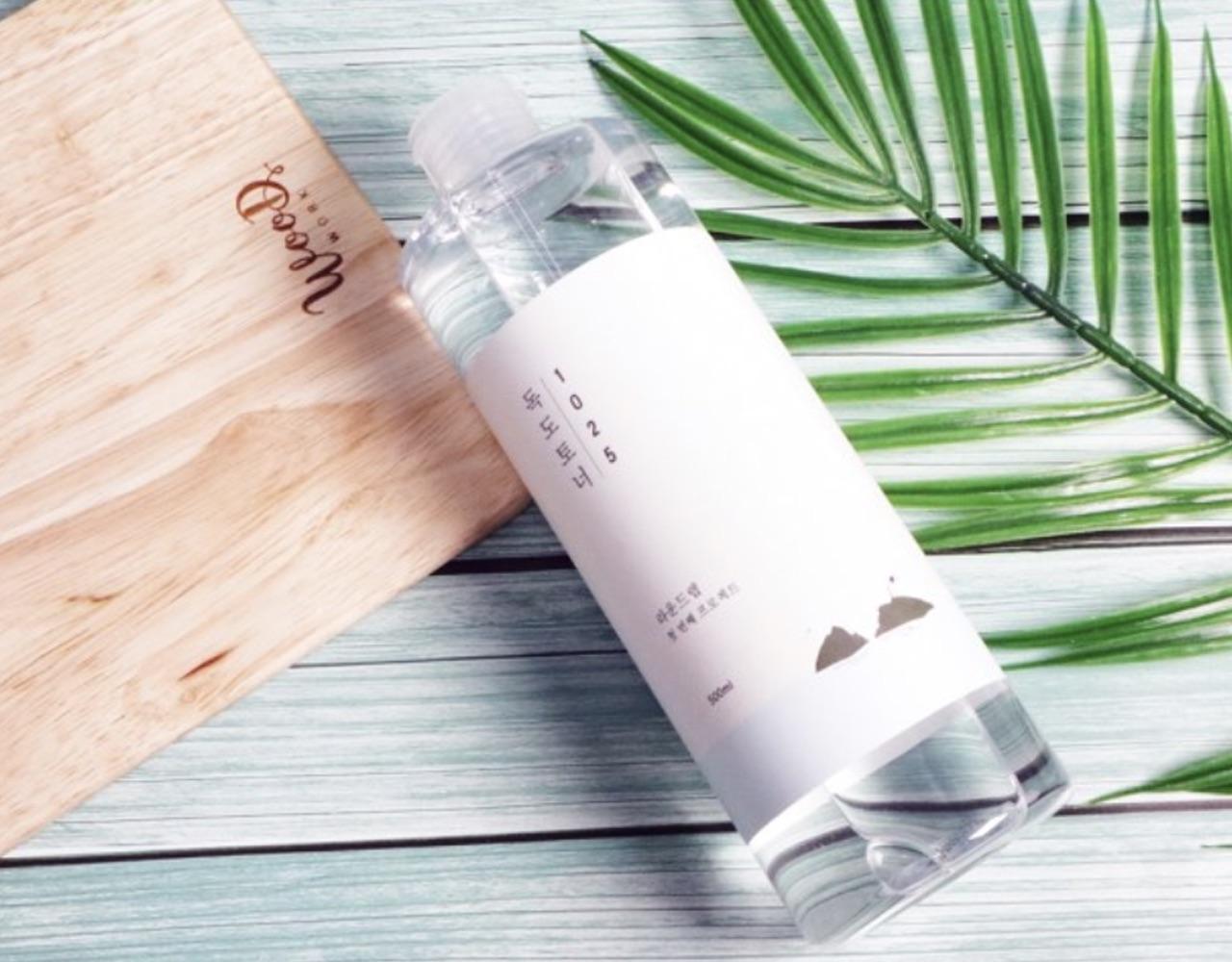 Korean brand round lab's dokdo toner bottle with wooden background and plant 