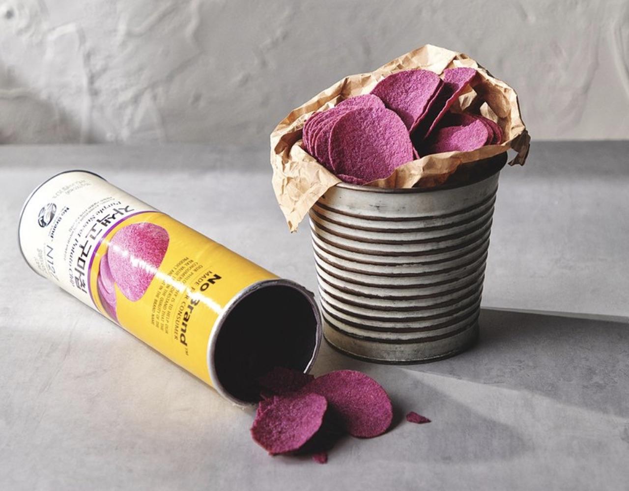korean brand no brand's purple sweet potato chip container on its side next to metal container full of chips