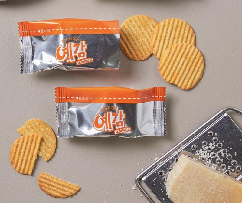 korean brand orion's yegam cheese gratin packs with cheese atop cheese grater in corner