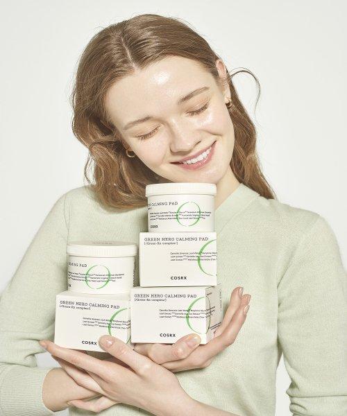 model holding up multiple containers of korean brand cosrx one step green hero calming pads 