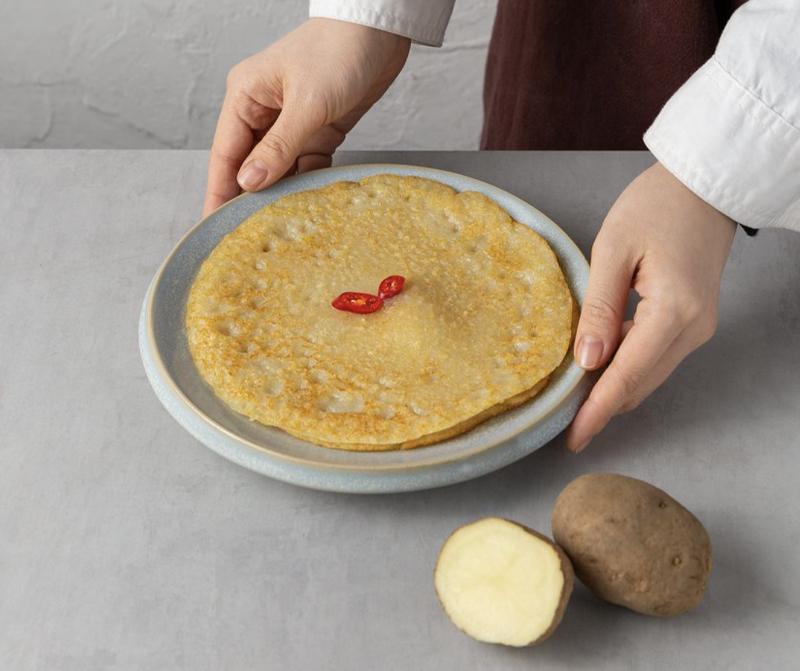 korean potato pancake on a plate next to potatoes