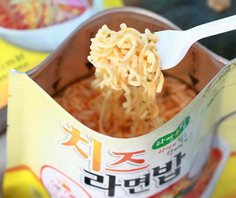 korean brand doori doori's cheese ramen rice with fork scooping up noodles from pouch