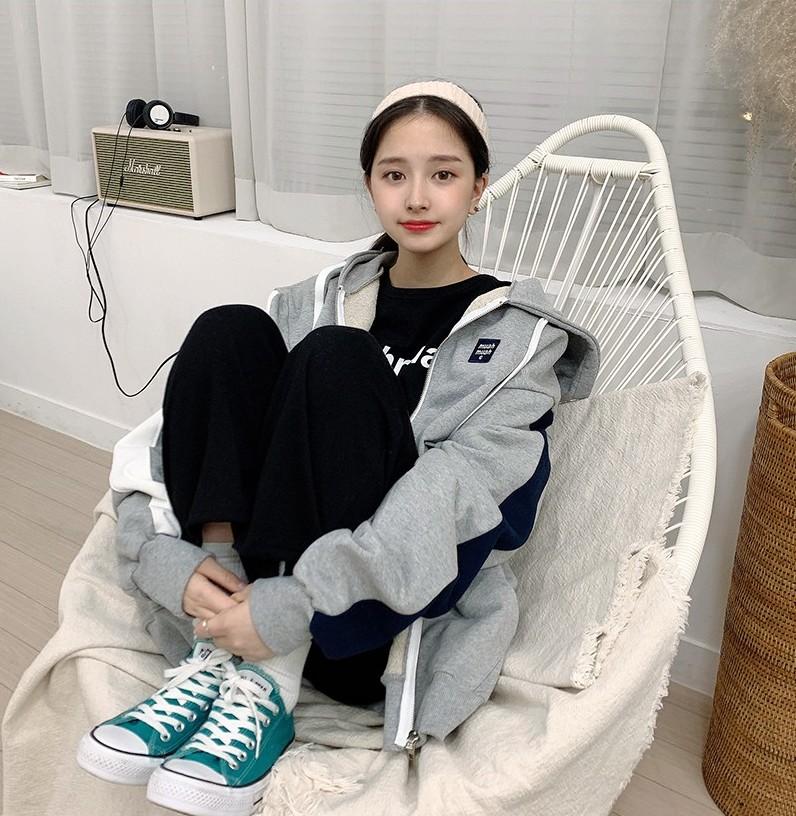 Korean brand muah muah signature combi hood zip up in gray worn by model sitting in white chair front angle