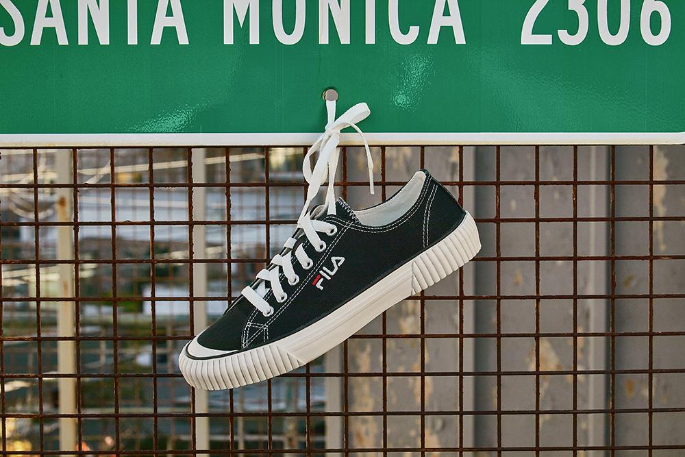 fila korea bumper shoe in black hanging from santa monica traffic sign by laces