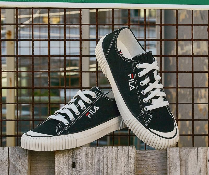 fila korea bumper sneakers in black posed on wooden fence