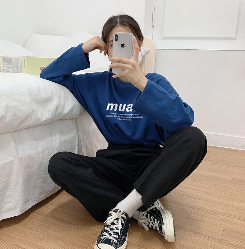 korean brand muah muah Signature Graphic T-Shirt in Indigo Blue worn by model sitting cross legged on ground next to couch taking a photo with phone
