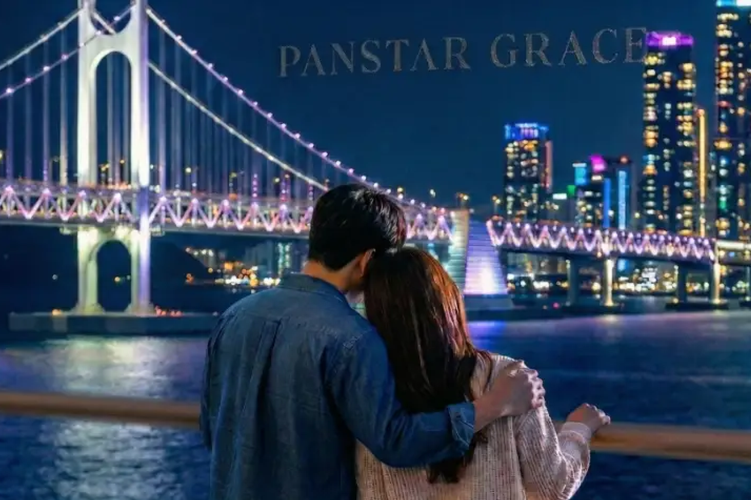 A couple looking out at Busan’s night view and bridge from a yacht